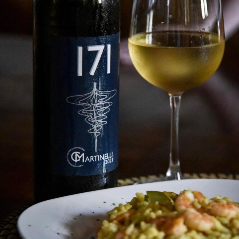 Bottiglia di vino bianco 171 Cantina Martinelli del 2021 affiancata da un calice di vino e un piatto di risotto con gamberi.