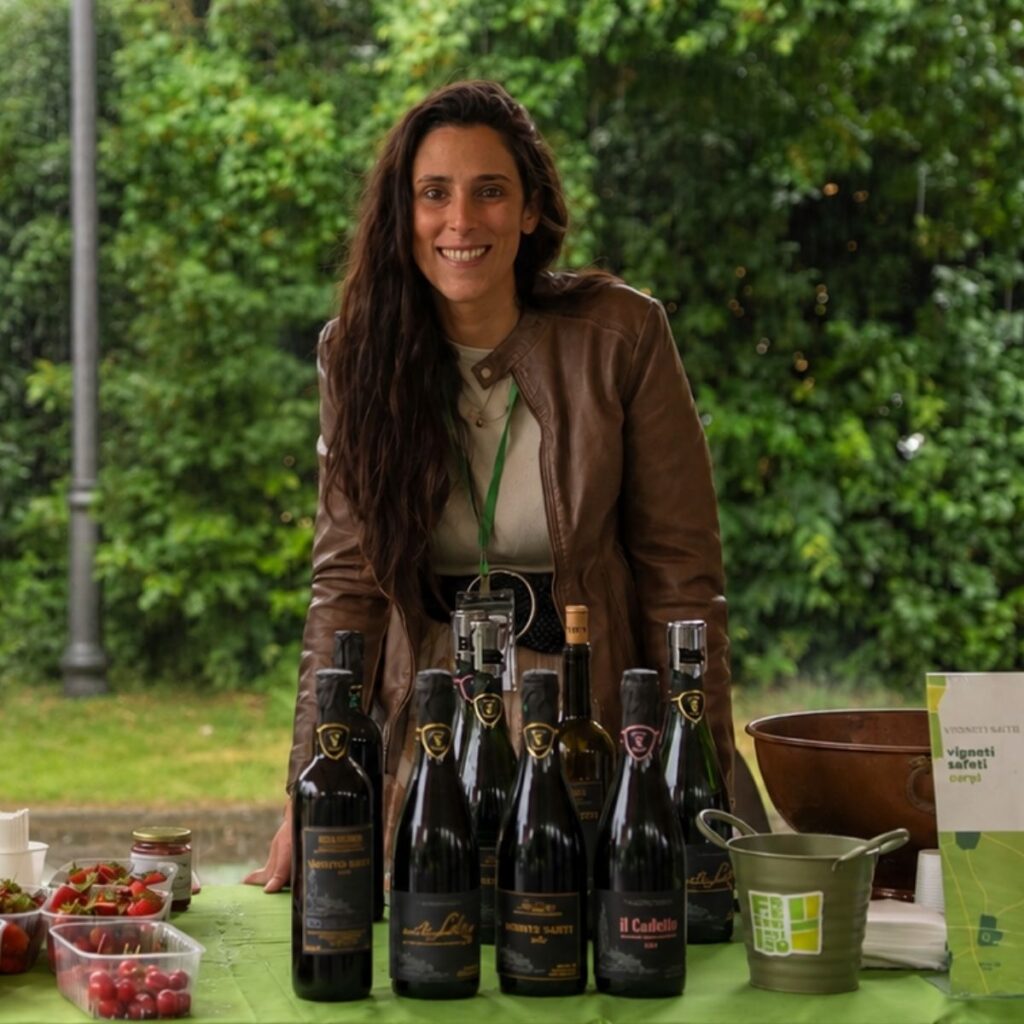 Ragazza sorridente dei Vigneti Saetti dietro al banco d'assaggio con la selezione di vini