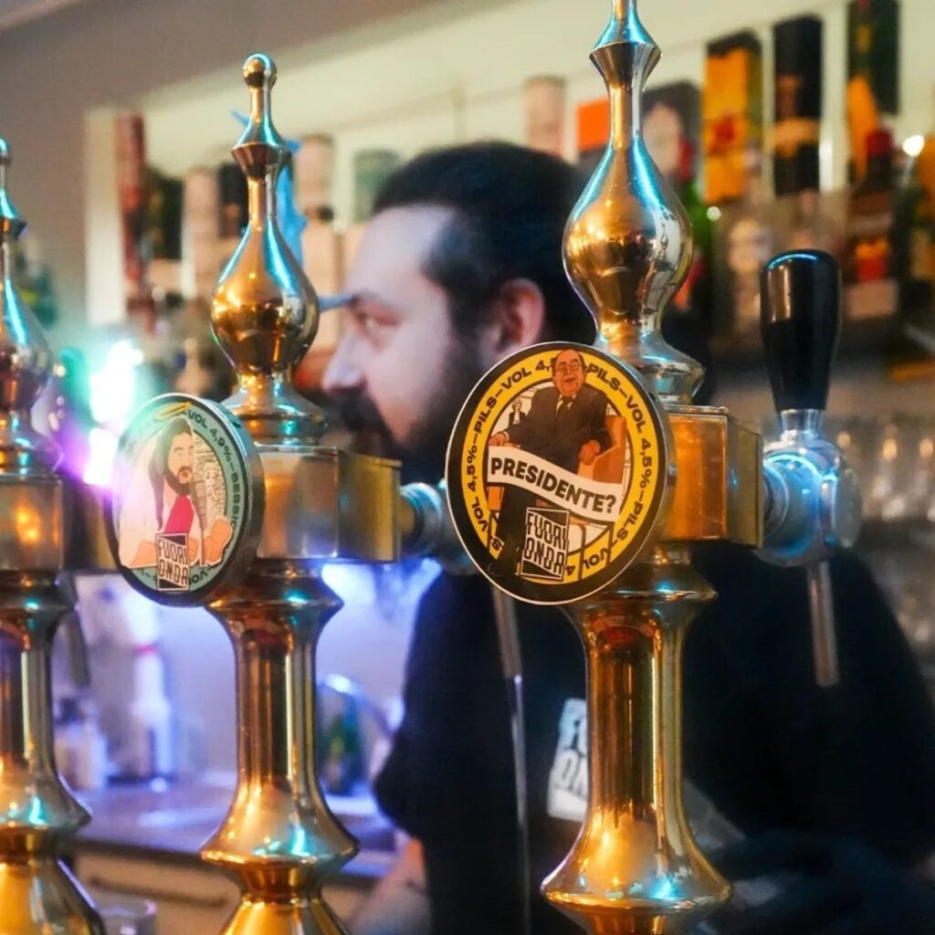 Dettaglio dei rubinetti dello spillatore con medaglioni della birra artigianale Fuori Onda.
