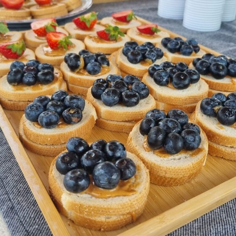 Vassoio di tartine dolci guarnite con crema, mirtilli e fragole fresche di stagione.