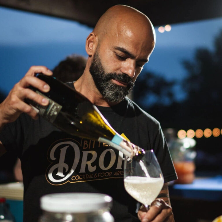 Bartender con maglia Bitter Drop versa una bevanda nel calice durante una serata dell'evento Freschissimo.